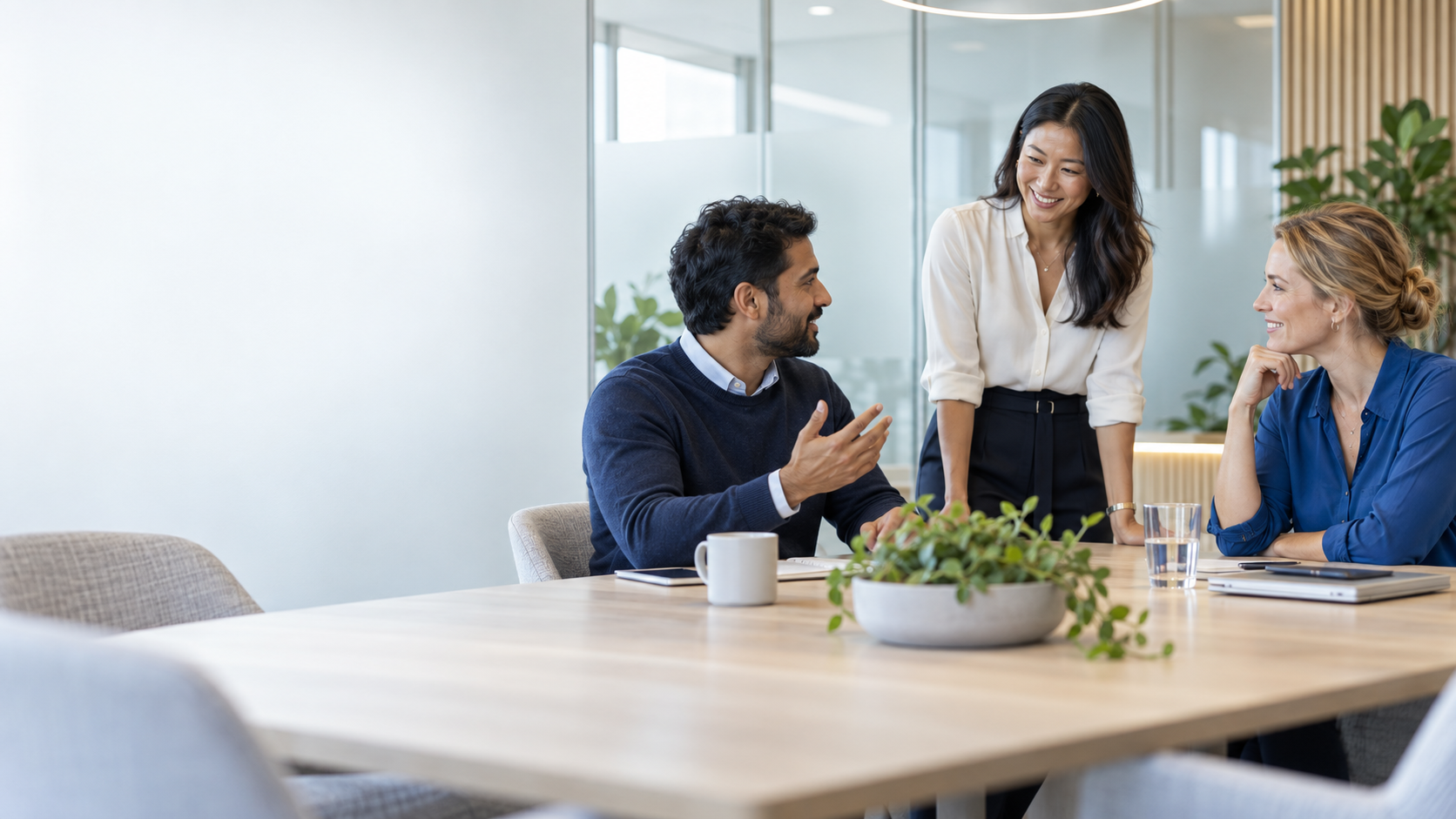 Three technology professionals having a thoughtful conversation in a bright contemporary office.